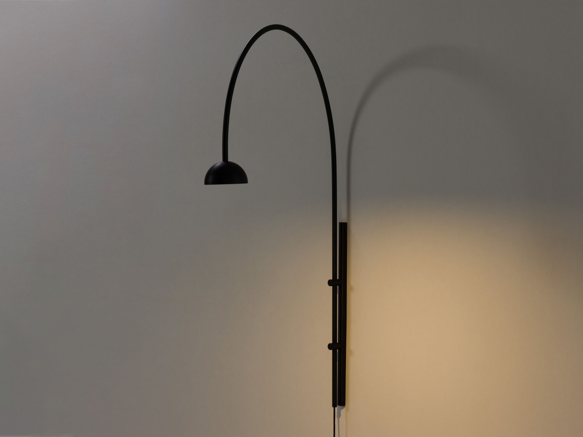 Large black arched wall lamp with light on front angle view